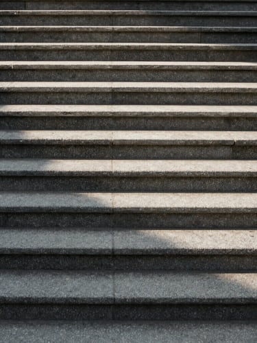 Soft indirect daylight casting long shadows across textured stone steps, minimalist architectural lines, calm and structured composition.