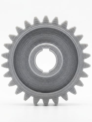 Macro shot of a 3D printed mechanical gear with visible precise layer lines, bright studio lighting, pure white background