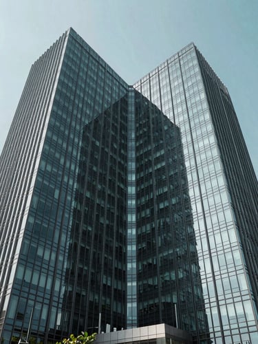 Symmetrical wide-angle architectural shot of a modern glass office tower in IT City Mohali, bright daylight, cool charcoal and teal tones, sharp focus