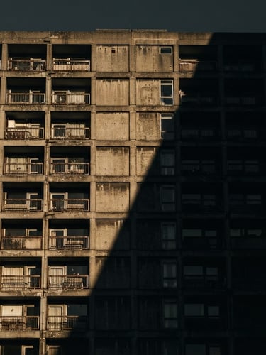 Stark architectural crop of a brutalist concrete facade in Shoreditch, sharp late-afternoon shadows cutting diagonally across the frame, high-contrast 35mm photography.