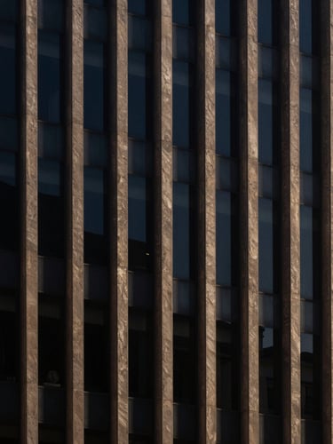 Architectural detail of a sober corporate building in São Paulo, sharp directional afternoon light, deep navy shadows, minimalist composition, 35mm