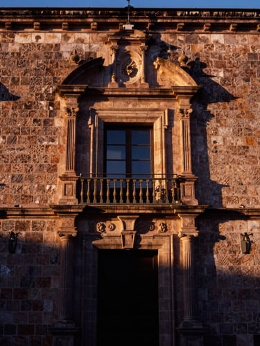 Environmental portrait of a historic stone building facade in Nochistlán de Mejía, traditional Zacatecas architecture, warm sunset light casting long shadows, prestigious and timeless atmosphere, 35mm film