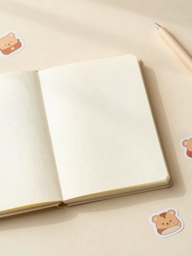 Overhead flatlay of an open cozy planner on a warm cream desk, surrounded by cute stickers and soft morning light, shallow depth of field