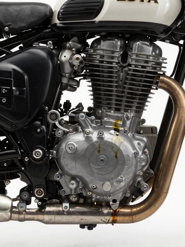 Tight close-up of a Royal Enfield engine casing and exhaust pipe, diffused north-facing studio light revealing casting texture and metal grain, oil traces visible on bolt heads, no rider or background, architectural framing