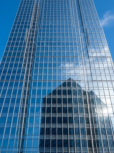 A towering modern skyscraper facade with crisp geometric glass reflections of blue sky and morning sun, architectural framing, 35mm lens