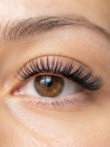 Extreme macro close-up of perfectly isolated eyelash extensions on a client's eye, soft diffused natural daylight, shallow depth of field, warm gold and soft pink tones, pristine, clinical-grade work.
