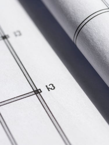 Macro close-up of sharp architectural blueprints under direct sunlight, clean geometric lines, high-contrast shadows, monochrome base.