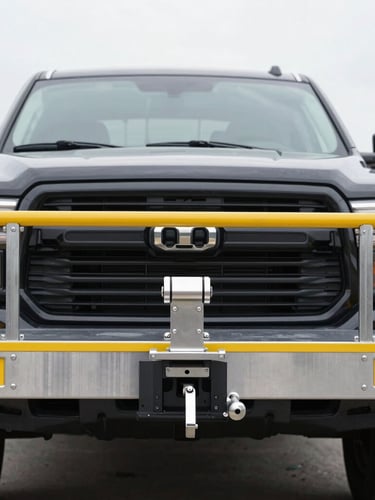 Straight-on eye-level shot of a clean steel utility trailer hitched to a modern black pickup truck, bright overcast daylight, sharp focus 50mm