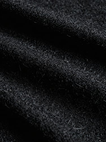Extreme close-up of heavy black wool fabric texture under harsh side light, high-contrast chiaroscuro, 35mm film grain