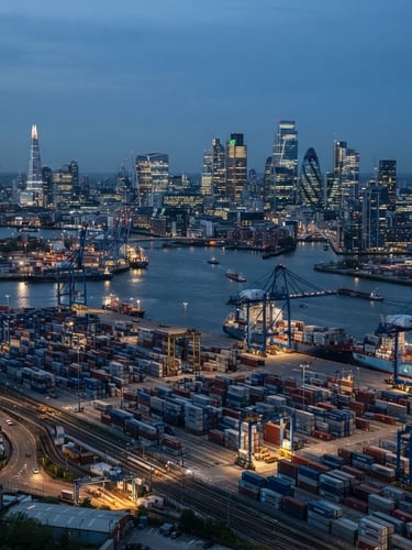 Wide view of a modern shipping port and high-tech corporate skyline at twilight, cool blue and slate tones, professional editorial style