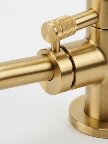 Extreme close-up of a brushed gold faucet, crisp metallic reflections, studio lighting on a clean white background, architectural detail, 50mm lens