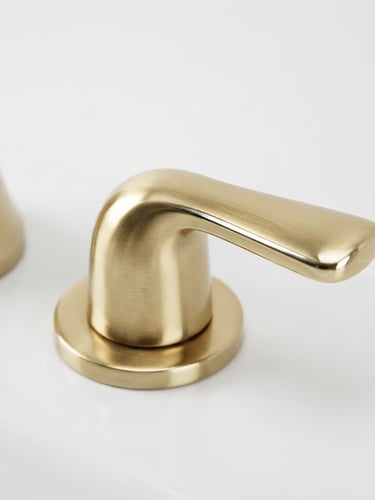 Extreme close-up of a brushed gold faucet handle, sharp metallic reflections, high-key studio lighting, minimalist white background, 50mm lens