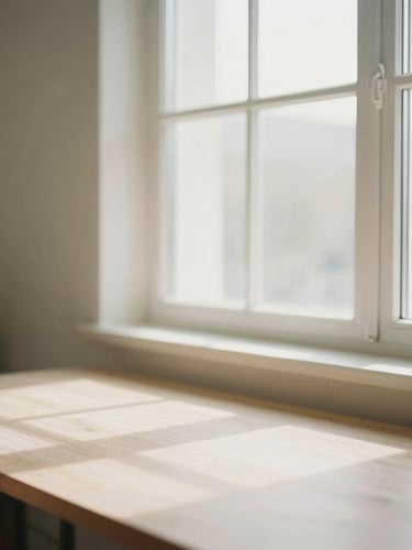 Warm editorial portrait of a clean, sunlit creative workspace, soft natural window light, muted neutral tones, minimalist aesthetic, shallow depth of field, 35mm