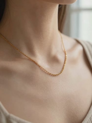 Macro shot of a solid gold chain necklace resting on a collarbone, warm natural window light, soft sandy neutral background, 35mm.