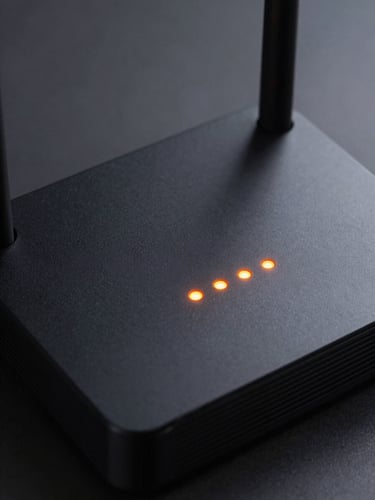 Macro shot of a sleek matte black home internet router with glowing orange LED indicator lights, sharp geometric framing, cool studio lighting.