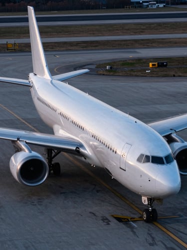 High-angle clean cargo aircraft on the tarmac, crisp cool twilight lighting with metallic silver reflections, wide environmental crop.