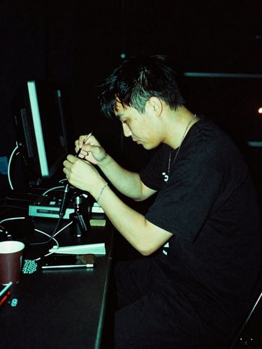 Low-key high-contrast photo of an artist backstage preparing under neon green lighting, 35mm film grain