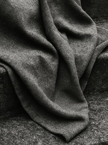 Close-up of heavy gray cotton fabric draped over a textured concrete step, overcast daylight, high contrast, 35mm film