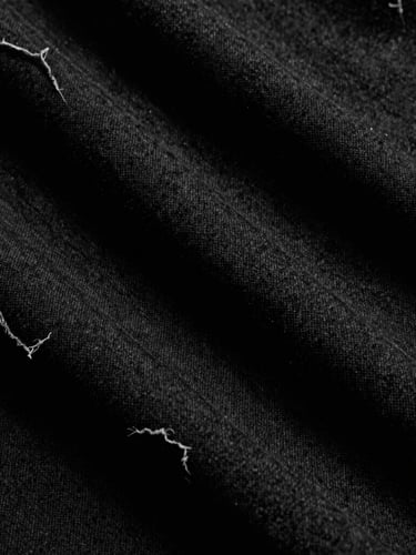 Extreme close-up of heavy black cotton fabric texture with raw, frayed edges, cast in dramatic high-contrast sunlight and deep shadows, moody monochrome 35mm film