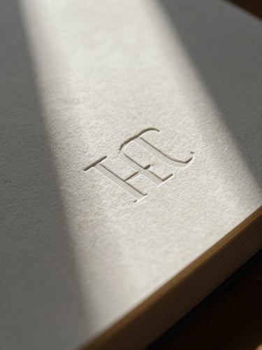 Macro close-up of heavy paper stock with letterpress ink indentations, soft directional window light casting deep shadows.