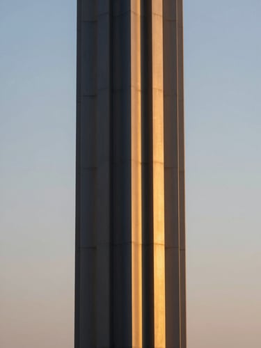 A close-up of premium warm gold metal finishes on a dark navy architectural column, soft twilight glow, medium format lens, editorial architectural photography
