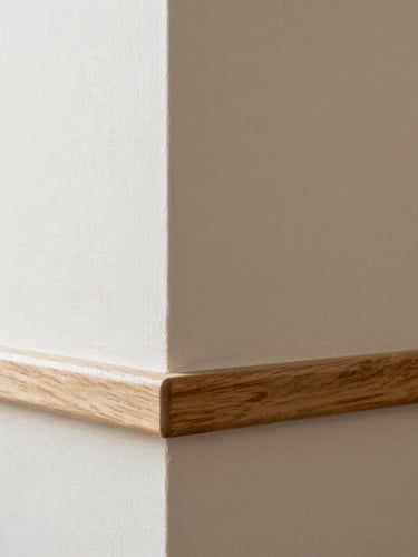 Architectural detail of a freshly painted wall meeting a natural wood baseboard, bright natural light, crisp lines, warm neutral tones, 35mm lens