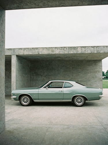 Side profile of a classic 1960s coupe parked in a minimalist concrete pavilion, soft overcast daylight, architectural framing, muted green and silver tones, 35mm film