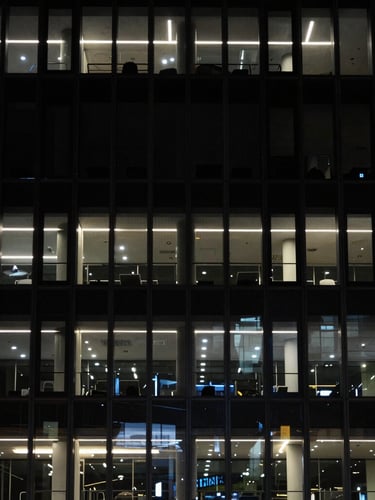 Architectural detail of a modern, secure office building facade at night, low-key dramatic lighting, sharp focus, dark tones, 35mm