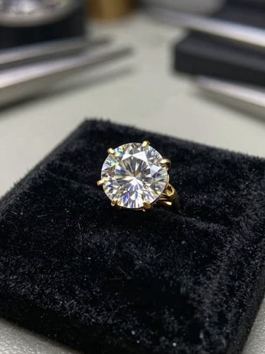 Extreme close-up of a single diamond set in a hand-fabricated gold mount on black velvet, soft north-facing light catching the facets, atelier workbench visible blurred in background