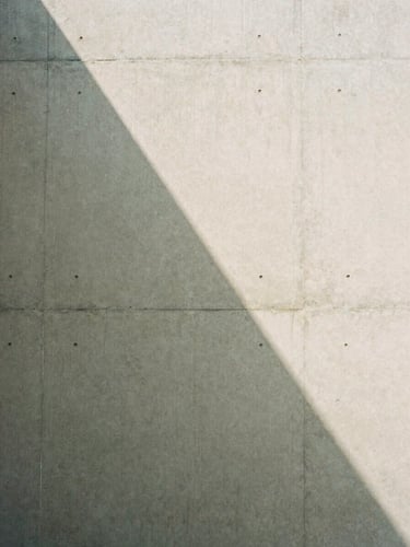 Detail of a concrete wall with a soft geometric shadow, minimalist architectural composition, natural light