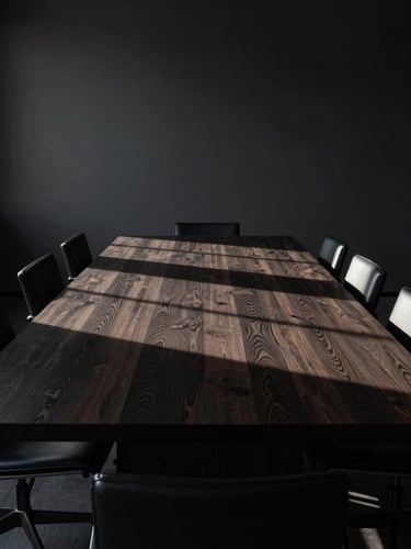 Low-key, dramatic side-lighting on a long, empty dark oak boardroom table with sharp geometric shadows, high-end minimalist interior, wide environmental shot.