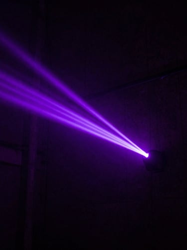 Extreme high-contrast overhead shot of a dark concrete urban alleyway at night, illuminated by a single sharp electric violet neon light beam, heavy atmospheric haze, 35mm photography