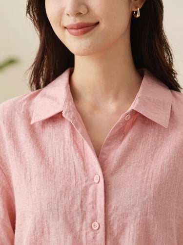 Close-up portrait of a smiling woman wearing delicate gold earrings and a rose pink linen shirt, soft natural daylight, warm editorial photography