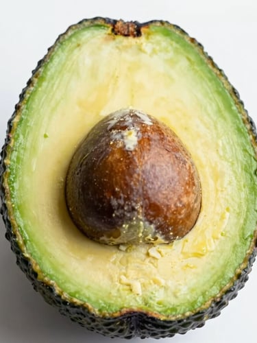 Close-up macro shot of a sliced ripe Hass avocado showing rich buttery green texture and a clean dark stone, bright natural daylight, clean white background
