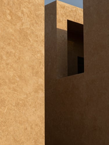 High-contrast architectural shadows on sand-toned concrete facades in Riyadh's financial district, sharp angles, minimalist composition, golden hour light.