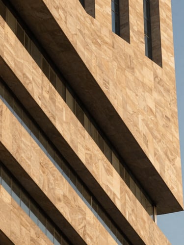 Abstract architectural geometry of a modern Riyadh skyscraper, sharp diagonal shadows against warm limestone, golden hour light, clean minimalist composition.