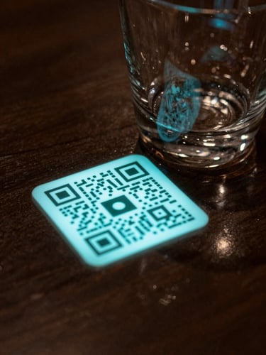 Extreme close-up of a fine-dining table surface in near-darkness, a luminous QR code card resting beside a polished glass, turquoise interface glow reflecting off the tabletop — no people, no diners, only the object and its light