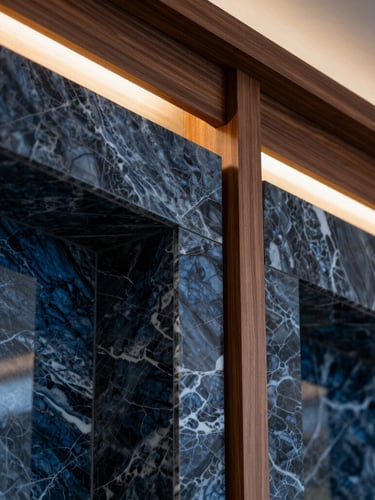 Macro close-up of luxury interior finishes, featuring book-matched marble panels meeting custom walnut wood joinery under warm architectural lighting