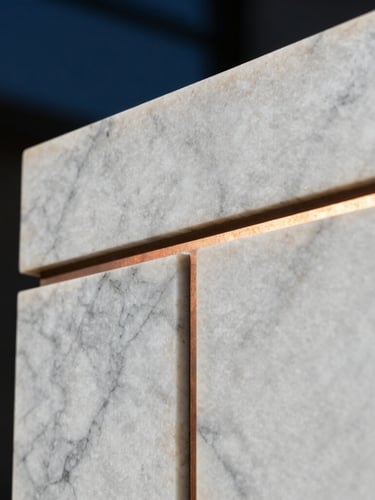 Extreme close-up macro shot of book-matched white marble with deep grey veins, accented by a warm glowing metallic copper joint, high-contrast architectural lighting