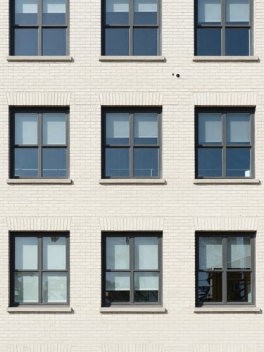 Architectural detail of a well-maintained commercial brick building exterior, clean windows, daylight, 35mm lens