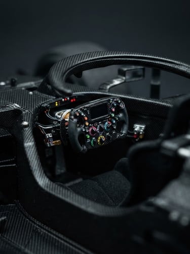 Macro close-up of a 1:18 scale Formula 1 miniature cockpit, showing extreme steering wheel details, carbon texture, dramatic studio lighting, deep charcoal background.