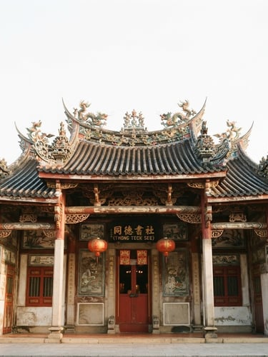 Low-angle architectural shot of a traditional Singaporean clan building facade, soft morning light reflecting on historic roof tiles, crisp white background.