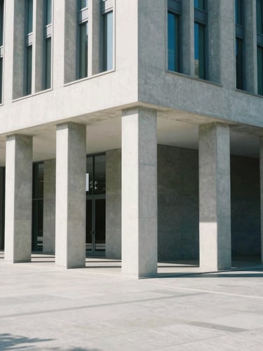 Wide architectural angle of a modern civic building with clean concrete columns, bright neutral daylight, sharp clean shadows, desaturated blues and grays