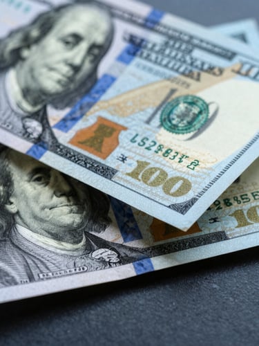 Macro detail shot of crisp physical hundred-dollar bills being counted under cool-toned studio lighting with sharp shadows, deep blue and silver tones.