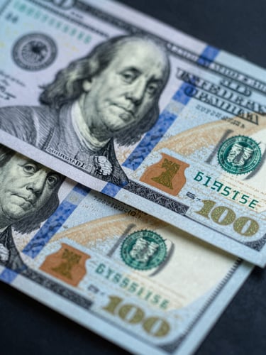 Macro detail shot of crisp physical one hundred US dollar bills being counted under cool-toned studio lighting, sharp high-contrast shadows, deep blue and silver tones.