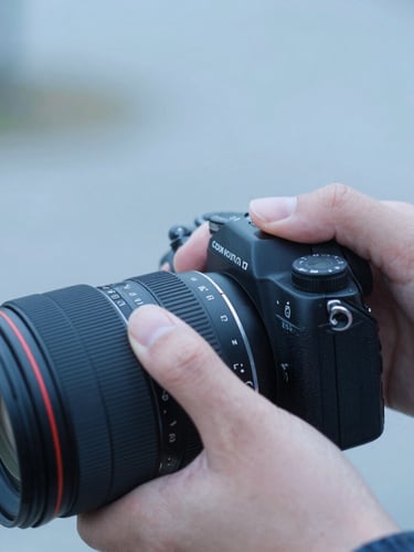 Close-up of hands adjusting a camera lens ring, soft diffused natural daylight, cool blue undertones, shallow depth of field, 35mm film look.