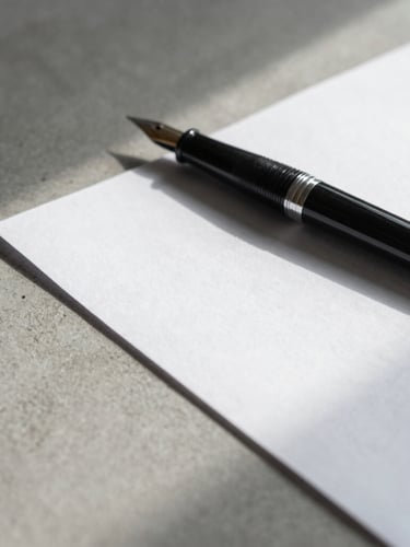 Macro photograph of a minimalist concrete desk surface, a heavy textured cotton paper document aligned parallel to a sleek black fountain pen, soft natural side shadow from a window.