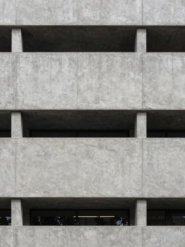 Straight-on architectural photograph of a modern Swiss concrete building facade, crisp geometric lines, soft diffused daylight, elegant and minimal.