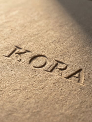 Extreme macro close-up of heavy, textured handmade paper with debossed organic branding, warm golden hour light casting deep shadows.