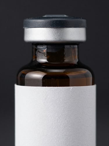 Extreme close-up portrait of a dark glass vial with a matte black cap and a crisp white label, sharp white studio light reflections on the glass surface, dark sterile background.